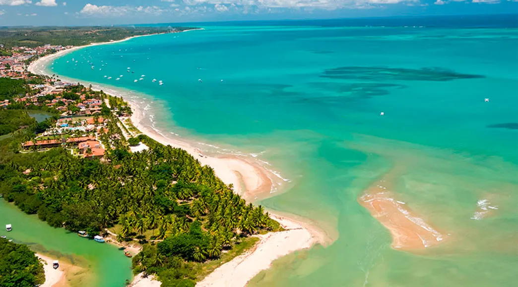 Praia de Maragogi Vista aérea da Praia de Maragogi, com águas cristalinas e ao fundo a cidade e vegetação.