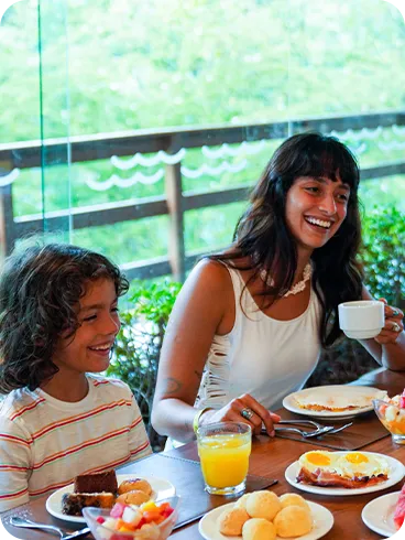 All inclusive no café da manhã Família sorrindo no restaurante, saboreando café da manhã com frutas, tapioca, ovos e café.