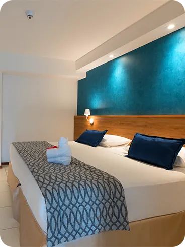 apartamento standard Cama queen size na acomodação Standard, em frente a roupeiro e painel de madeira com TV a cabo, mesa e cadeira.