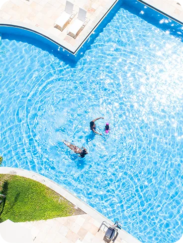 Piscina do Salinas Maceió Vista aérea da piscina principal do Salinas Maceió com família nadando e reflexos de sol na água azul.