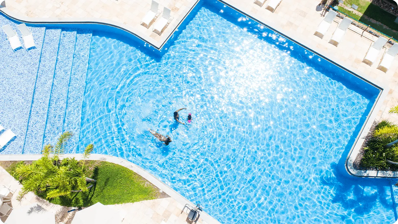 Piscina do Salinas Maceió Vista aérea da piscina principal do Salinas Maceió com família nadando e reflexos de sol na água azul.