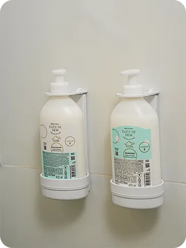 Dispensers de Refil O Boticário Shampoo e condicionador O Boticário, da linha Cuide-se Bem, em frascos de refil instalados em dispensers na parede de azulejos do banheiro.