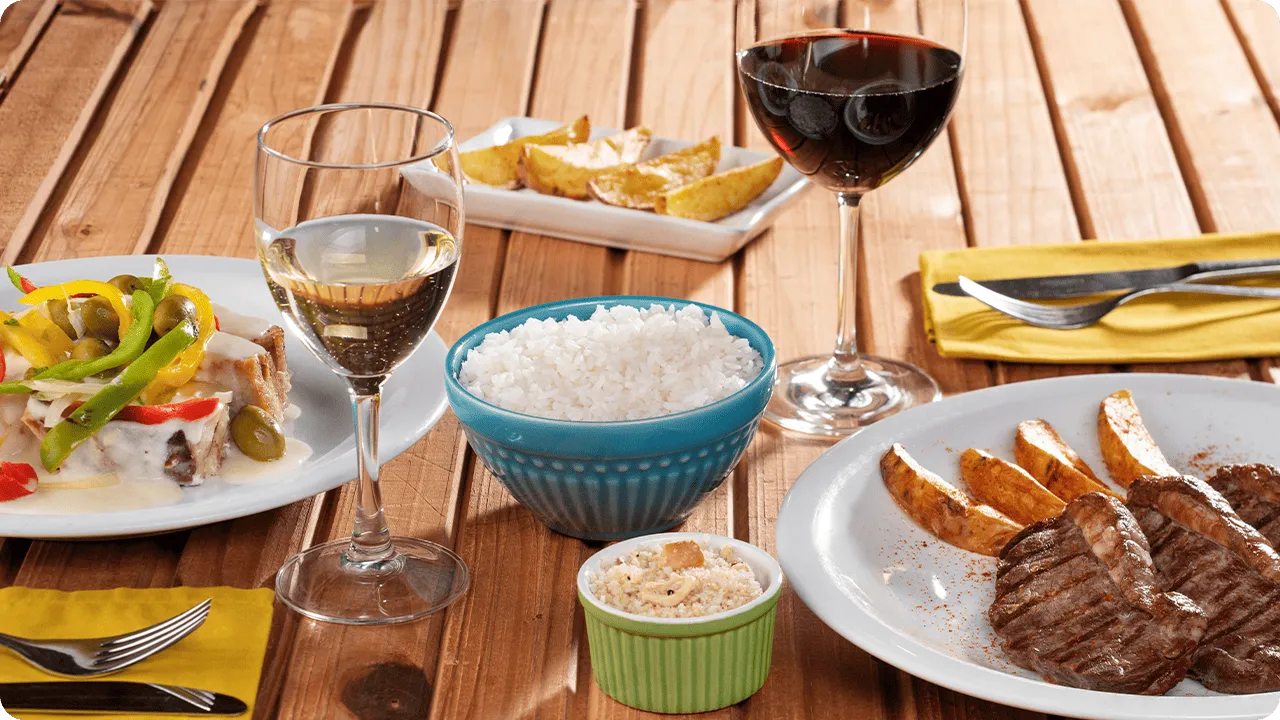 All Inclusive de verdade Prato de bacalhau e pedaços de carne assada acompanhadas de batatas rústicas, arroz e vinhos.