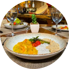 Jantar em família no melhor resort na praia Jantar com camarões ao molho, arroz branco, farofa e taças de vinho branco servido em ambiente acolhedor com mesa posta pra três pessoas.