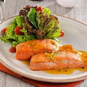 Jantar all inclusive Filés de salmão ao molho com salada, taça de espumante e garrafa ao fundo em mesa de restaurante