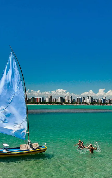 Como chegar em Maceió Vista das águas cristalinas e jangada em Maceió com a cidade ao fundo