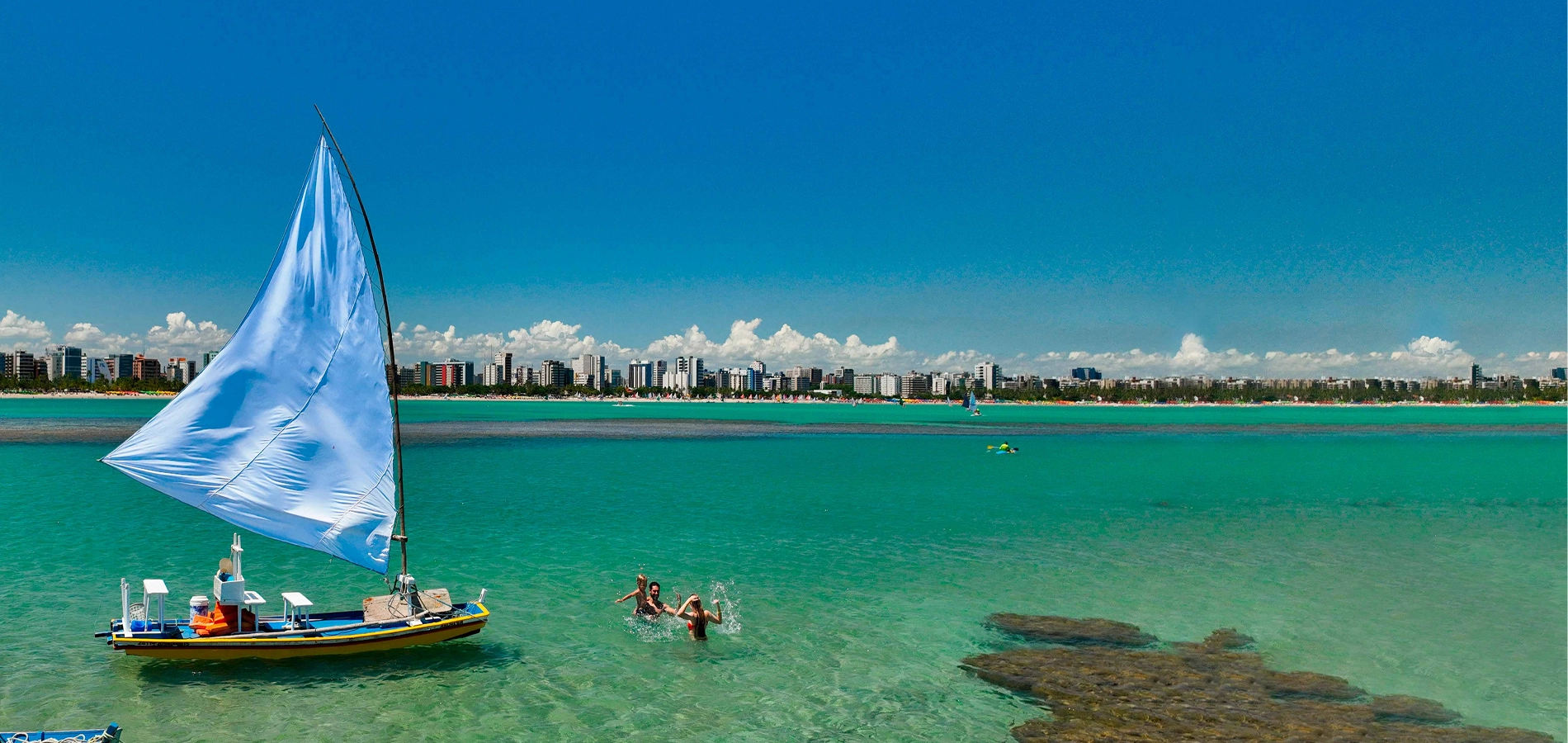 Como chegar em Maceió Vista das águas cristalinas e jangada em Maceió com a cidade ao fundo