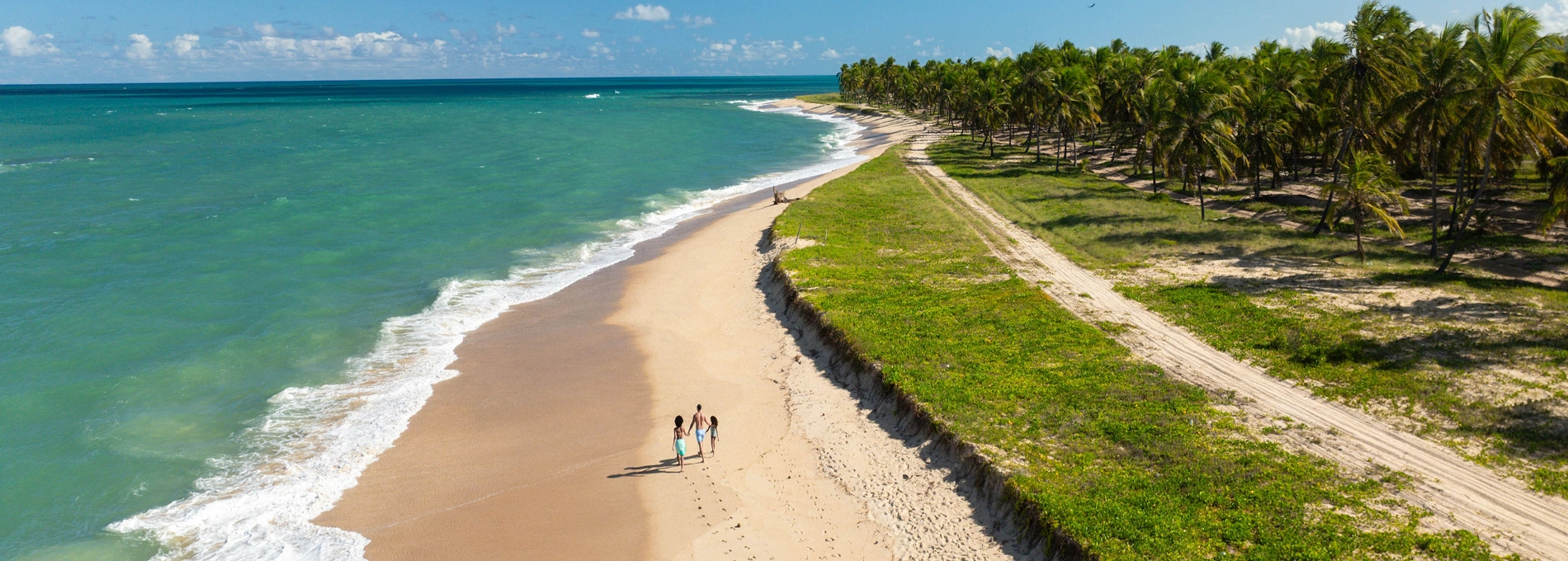 contato salinas Família caminha sobre areia branca à beira-mar da praia do Gunga, em Alagoas.