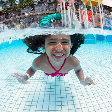 Resort para crianças Criança se divertindo debaixo d'água na piscina do resort.