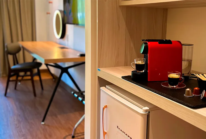 victória-régia Baño en el Standard Vitória-Régia, con un espejo de forma orgánica sobre el lavabo, toallas dispuestas en la encimera y colgadas junto al lavabo, un espejo de aumento, secador de pelo, decoración y artículos de tocador L'Occitane.