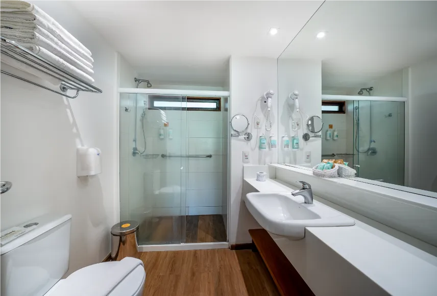 Baño de la Suite Familiar Baño de la Suite Familiar con zona de baño, inodoros, ducha con control de temperatura, decoración, artículos de aseo O Boticário, toallas, un espejo grande y secador de pelo.