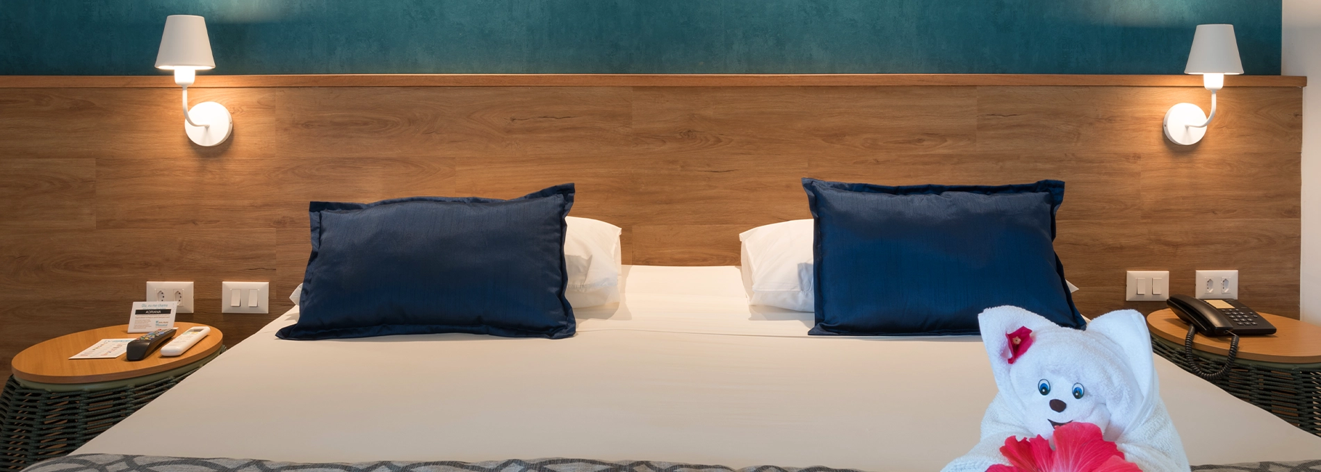 standard salinas maceio Acomodação Standard, uma das acomodações do Salinas Maceió All Inclusive Resort, com uma cama queen size aconchegante no centro, painel de madeira atrás da cama com duas luminárias e duas mesas de cabeceira, uma em cada lado da cama.