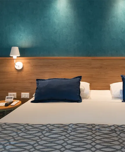 standard salinas maceio Acomodação Standard, uma das acomodações do Salinas Maceió All Inclusive Resort, com uma cama queen size aconchegante no centro, painel de madeira atrás da cama com duas luminárias e duas mesas de cabeceira, uma em cada lado da cama.