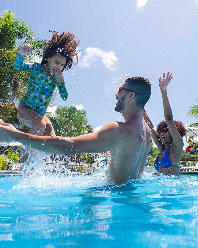 resort nordeste Família aproveita a piscina do Salinas Maceió. Pai e mãe recebem de braços aberto o pulo da filha na água cristalina.