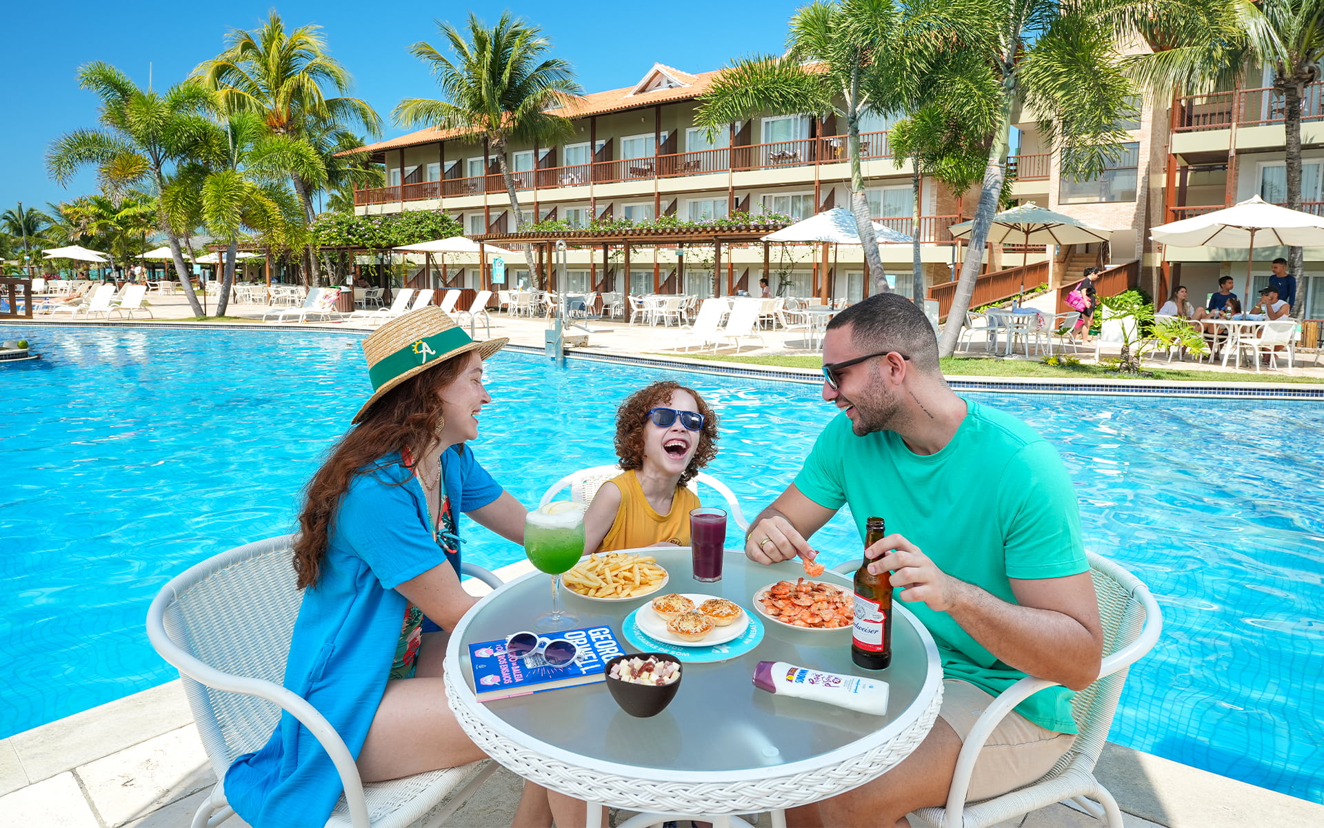 Petiscos e bebidas na beira da piscina Família aproveitando os petiscos camarão, batata frita, empada com cerveja, drink e suco na beira da piscina do Salinas Maceió.