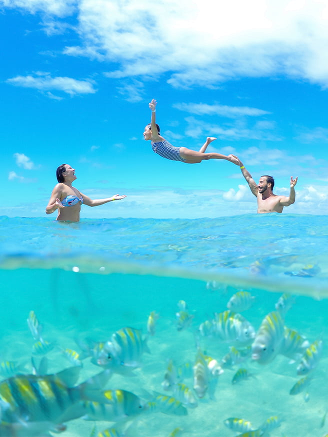 Piscinas naturais de Paripueira Família se divertindo nas piscinas naturais de Paripueira. Com foto meia submersa, na parte inferior está abaixo d'água com peixinhos e acima, o pai jogando a filha pra cima em direção a mãe com dia ensolarado.