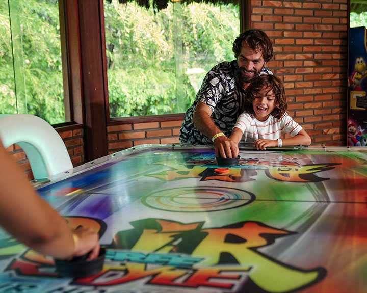  Pai e filho brincando no aero hockey no Espace Teen, área de lazer do Salinas Maragogi.