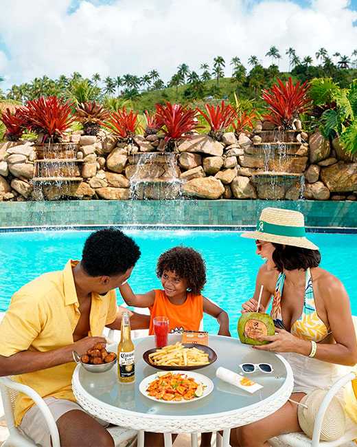 Família aproveitando refeições na beira da piscina.