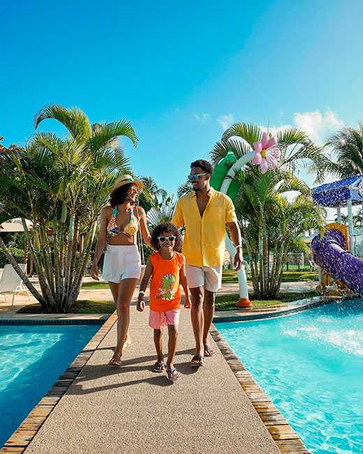 Família caminhando ao lado da piscina no resort Salinas Maragogi.