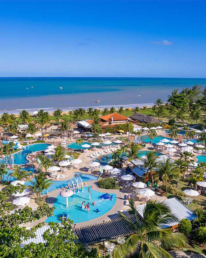 piscina salinas maragogi Área externa do Salinas Maragogi mostrando as principais piscinas, as infantis com os brinquedos. Com várias espreguiçadeiras, guarda-sóis, o céu esta azul sem nuvens, mar calmo e azul. A estrutura do resort é cercada por coqueiros.