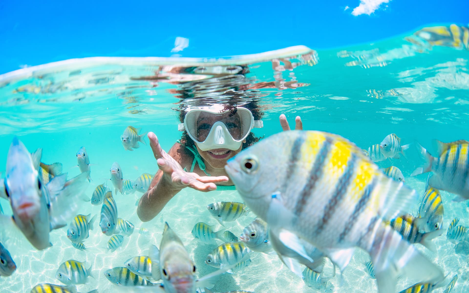 Descobertas nas piscinas naturais de Barra Grande Criança mergulhando nas águas cristalinas de Barra Grande com peixes coloridos ao seu redor.
